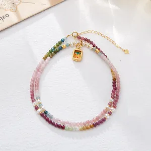 Detalle del collar de cuentas con turmalina de colores, perlas y colgante dorado pintado