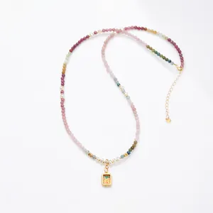 Collar de turmalina arcoíris y perlas con colgante thangka dorado sobre fondo blanco