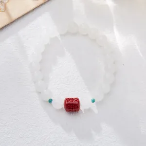 Detailed view of white jade beads with cinnabar mantra barrel and turquoise spacers