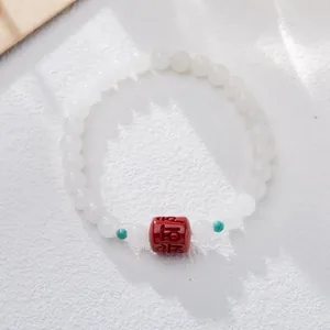 Detail of white jade beads bracelet with red cinnabar bead and small green spacers