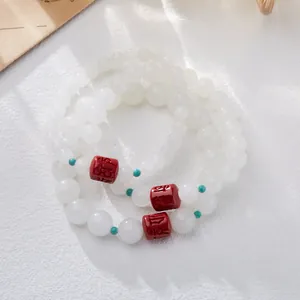 Macro detail of Hetian white jade beads with red cinnabar barrel charms and turquoise spacers