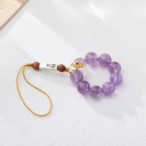 Macro view of purple amethyst beads and silver charm with Auspicious engraving
