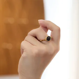 Bague dorée style bambou avec pierre noire sur main de femme, esthétique chinoise