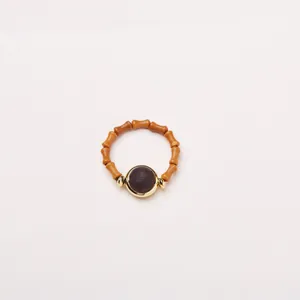 Vue détaillée d'une bague en bois style bambou avec pierre rouge et métal doré
