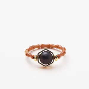 Détail d'une bague en bois en forme de bambou avec cadre doré et perle noire centrale