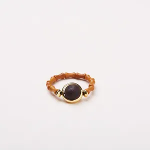 Gros plan d'une bague en bois en forme de bambou avec cadre doré et perle centrale