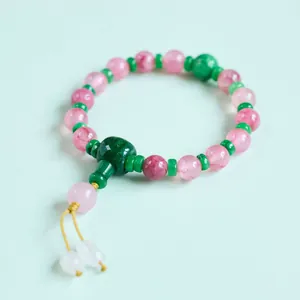 Dettaglio macro di perle di cristallo rosa e distanziali verdi su bracciale cinese