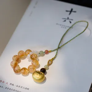 Close-up of yellow crystal bead pendant with gold Fu charm on minimalist book