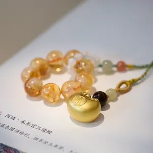 Macro shot of natural yellow crystal beads and golden Fu character lock pendant charm