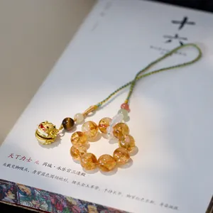 Macro shot of citrine beads and enamel beast charm pendant on an artistic book page
