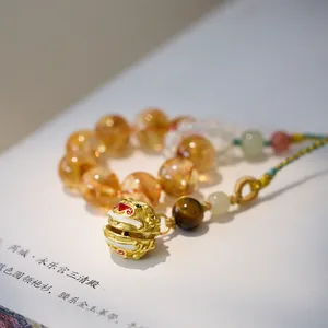 Macro detail of amber crystal bead bracelet with enamel lion pendant and tiger eye stone