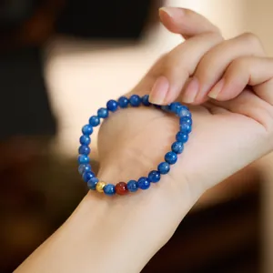 Natural 6mm blue kyanite beaded bracelet on wrist with gold accent and red bead detail