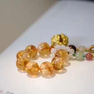 Macro shot of citrine beads with golden metal charms on a hand-woven brown cord