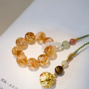 Macro shot of amber crystal beads and golden tiger bell with intricate woven silk cords