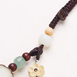 Macro shot of handcrafted woven keychain with white Bodhi beads and a wooden flower pendant