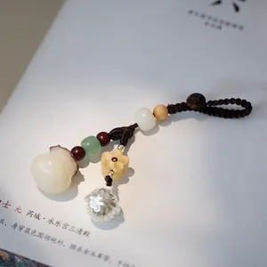 Detailed close-up of a handcrafted Bodhi seed charm with a bell and wood beads