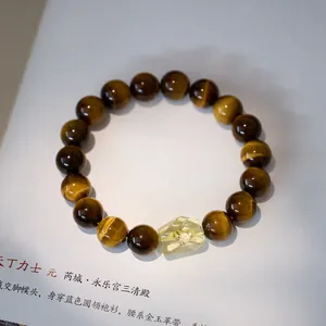Macro detail of natural 10mm tiger eye stone beads and faceted yellow crystal pendant