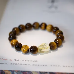 Macro detail of natural tiger eye beads and yellow crystal on a stretch bracelet