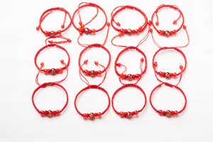 Detail showing 12 hand-woven red string bracelets with golden Chinese zodiac beads