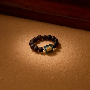 Detailed macro view of an agarwood bead ring featuring green jade and golden relief