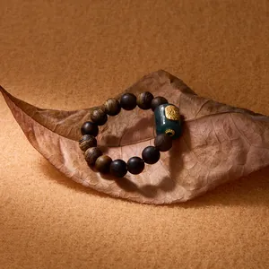 Detail of a natural wood bead bracelet with a green jade bead and golden relief accents