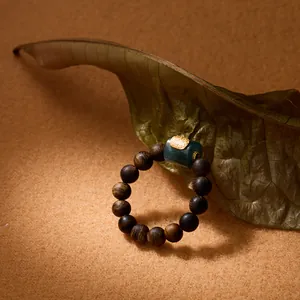Agarwood bead bracelet with green jade barrel bead on a zen nature background