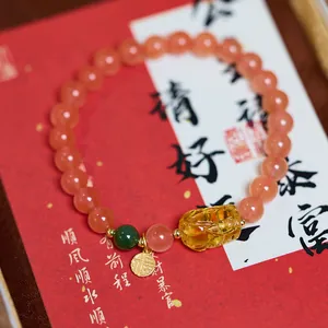 Detail of red agate bracelet with yellow amber Pixiu pendant and gold Fu charm