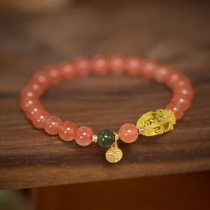 Detail of red agate bracelet with yellow PiXiu charm and gold Fu character tag