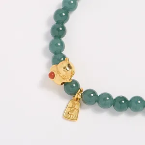 Detalle macro de pulsera de jade 6mm con gato de la suerte dorado y colgante grabado