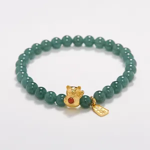 Detalle macro de cuentas de jade verde natural con gato de la suerte dorado y amuleto Fu