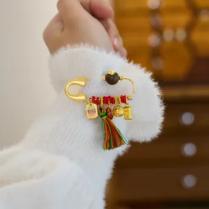 Détail d'une broche dorée ornée avec un gland coloré sur une manche en peluche blanche