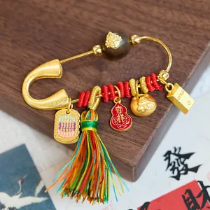 Détail de la broche dorée avec gourde en émail, glands colorés et pendentifs sacrés