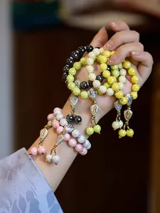 Detail von farbenfrohen Keramikperlenarmbändern mit Vajra-Anhängern und Quasten im Zen-Stil