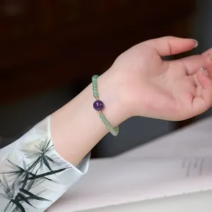 Grünes Perlenarmband mit 8mm Amethyst und goldenen Akzenten am Handgelenk getragen