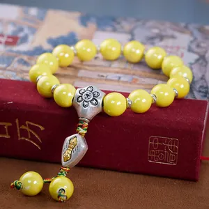 Nahaufnahme der buddhistischen gelben Porzellanperlen mit silbernem Vajra-Anhänger
