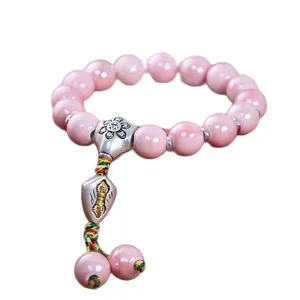 Rosa glasiertes Perlenarmband mit silbernem Vajra-Anhänger auf weißem Hintergrund