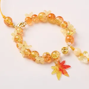 Detail of beaded keychain with autumn orange crackle beads and a maple leaf charm
