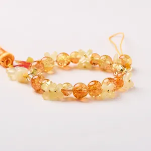 Orange beaded charm with yellow flower accents and orange silk tassel on grey background