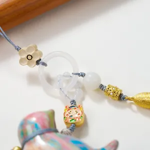 Detail of a colorful lacquered cat charm with imitation jade ring and golden tassels