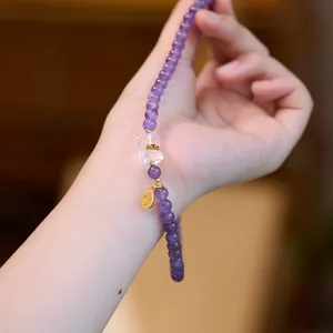 Détail du bracelet en améthyste naturelle avec breloque ours et médaille Fu dorée