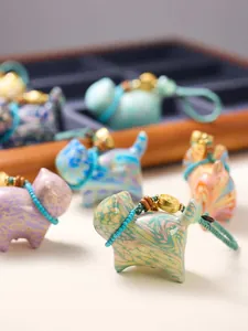 Close-up of colorful lacquer lucky cat charms with marble texture and woven lanyards