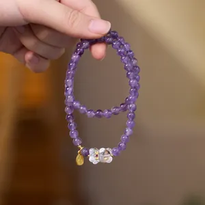 Détail du bracelet en perles d'améthyste avec breloque renard blanc et étiquette dorée