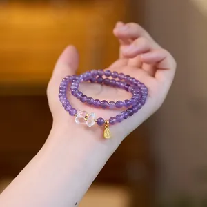 Vue détaillée du bracelet double rang en améthyste violette avec papillon et breloque dorée