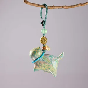 Close-up of a colorful ceramic cat charm with Fortune tag hanging on a branch