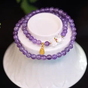 Détail macro du bracelet double couche en améthyste violette avec pendentif porte-bonheur
