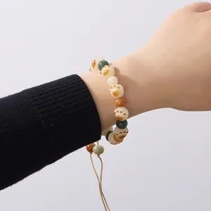 Close-up of cat paw beads and multicolor stones on an adjustable braided bracelet
