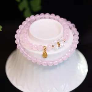 Gros plan de perles en quartz rose avec pendentif Fu doré et breloque renard