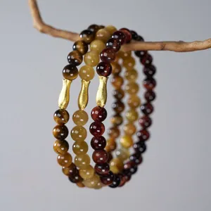 6mm Tiger Eye stone bracelet set with golden fish charms on natural wood branch