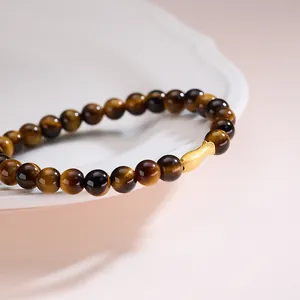 6mm tiger eye bead bracelet with a golden peanut charm on a white ceramic plate