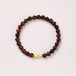 Detailed shot of 6mm tiger eye beads with a gold fish charm in a retro style